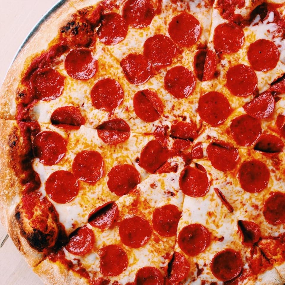A freshly baked Mikey's Pizza pepperoni pizza, cut into slices, with melted cheese and a crispy crust.