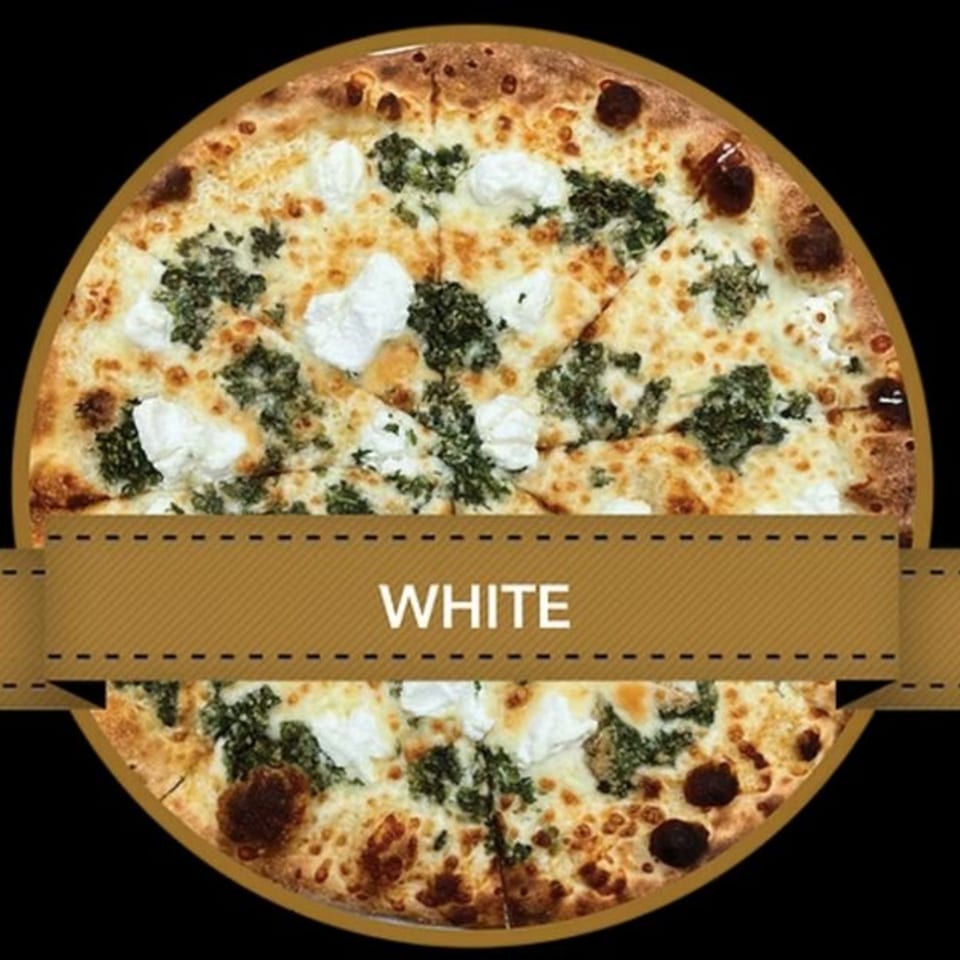 Mikey's Pizza white pizza with dollops of ricotta cheese and green pesto on a dark background.